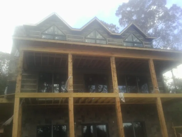 Dormers and porch framing on a large log home under construction — Roof Coating work by our crew in Randolph