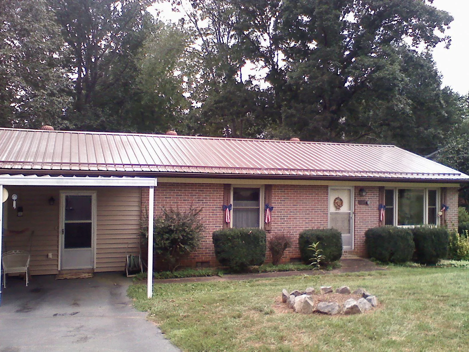 Bronze metal roof and carport on a brick ranch home — Roof Repair work by our crew in Randolph